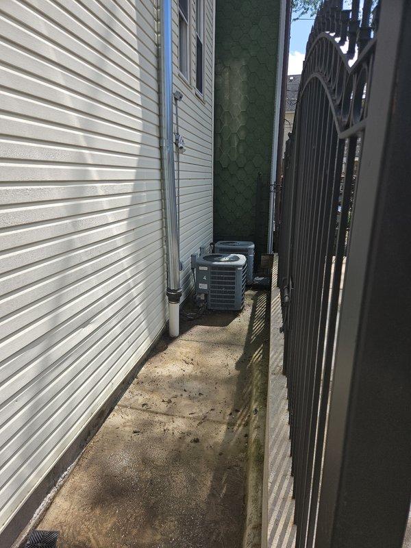 Responded to a residential drainage issue where a sidewalk drain cover had come off and the drain basin was completely filled with dirt and debris. Accessed the property through the rear alley to assess the ground-level drain located along the side walkway near the building exterior. Documented the condition of the concrete pad showing weathering, the exposed drain opening, and surrounding deterioration requiring cleanout and potential drain cover replacement to restore proper drainage function.