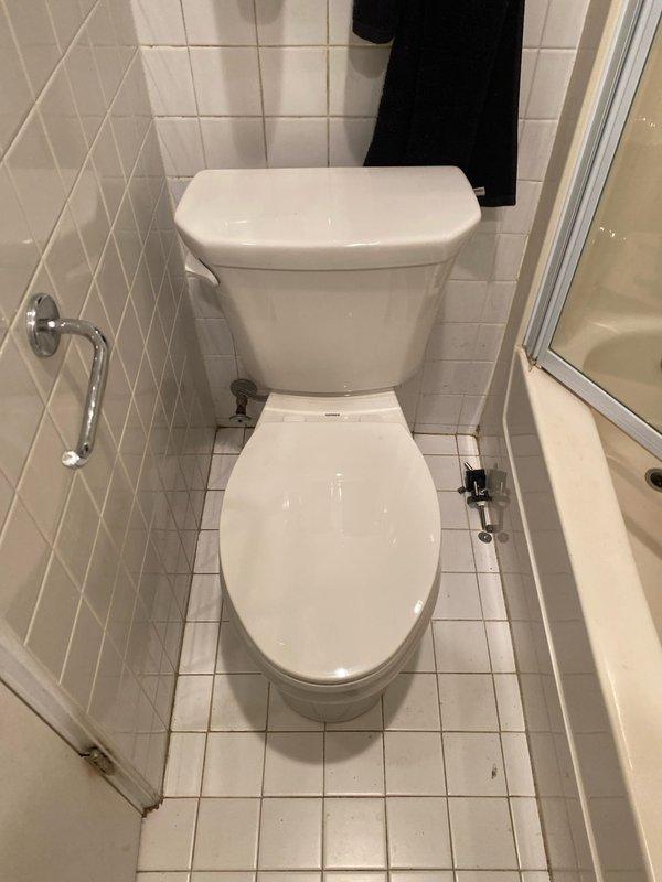 Completed toilet installation in residential bathroom with white tile flooring and walls. Removed existing toilet fixture that showed significant water damage and brown staining around the floor flange area, indicating previous leakage or seal failure. Installed new wax ring seal and properly seated toilet on flange to prevent future water seepage. Connected water supply line and tested for proper flush operation and leak-free performance.