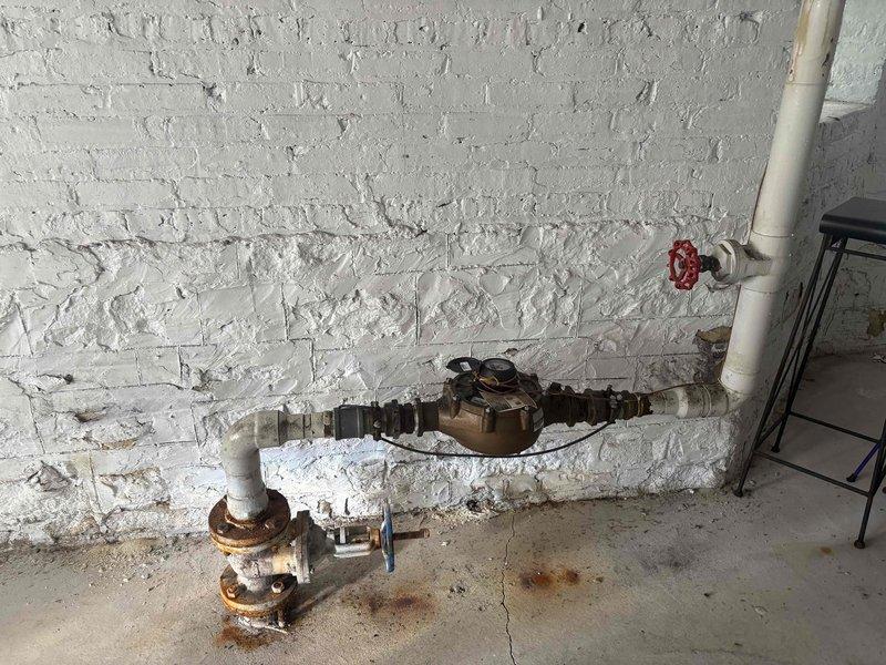Conducted site inspection of main water shutoff valve and 3-inch valve/nipple assembly at 12-unit condominium building as flagged by City Water Department. Assessed heavily corroded main shutoff valve, flanged pipe fittings, and associated piping components showing extensive rust deterioration and oxidation throughout the assembly. Documented condition of bronze water meter, corroded valve body with flanged connections, and deteriorated bolted flanges requiring replacement to meet municipal requirements. Provided comprehensive estimate for replacement of 3-inch valve assembly and coordination with City Water Department for completion of their work.
