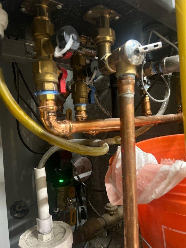 Completed plumbing estimate for dual tankless water heater installation with comprehensive piping assessment. Documented existing copper supply lines, brass valve configurations, PVC venting system, and pressure monitoring equipment. Photographed complete mechanical assembly including gas connections, exhaust routing, and control components for proposal development.