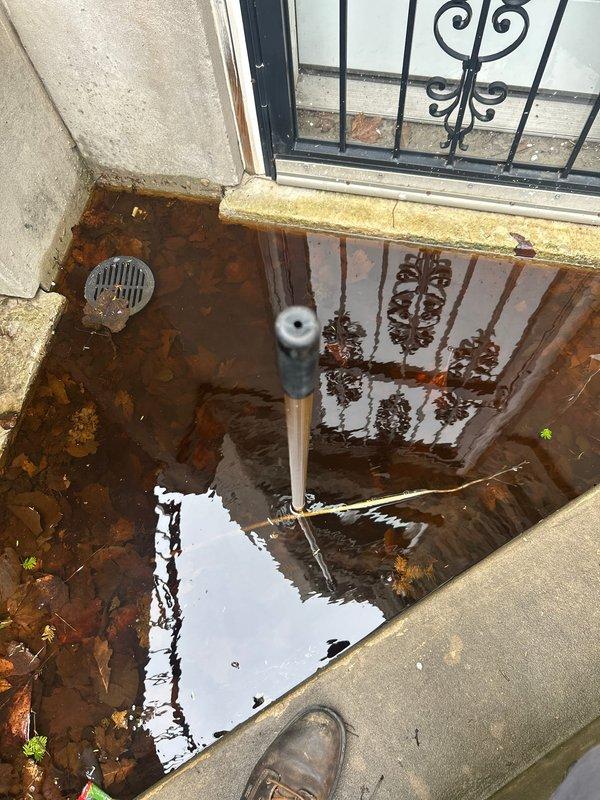 Responded to a clogged outdoor drain causing severe flooding in an exterior basement stairwell. Deployed rodding equipment to clear the blockage from the below-grade drain system, which had resulted in standing water completely submerging the lower stairwell area. Successfully cleared the obstruction and restored proper drainage function to the outdoor drain line.