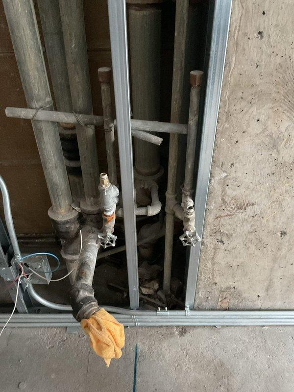 Responded to service call for kitchen renovation plumbing work. Assessed existing galvanized piping system in exposed wall cavity for potential conversion to copper supply lines and evaluated installation requirements for new ice maker water line. Building water supply was coordinated for 10am shutdown to facilitate the plumbing modifications. Documented existing pipe conditions and framing layout in mechanical space to develop comprehensive estimate for replacing aged galvanized valves with copper alternatives and establishing dedicated ice maker connection point.