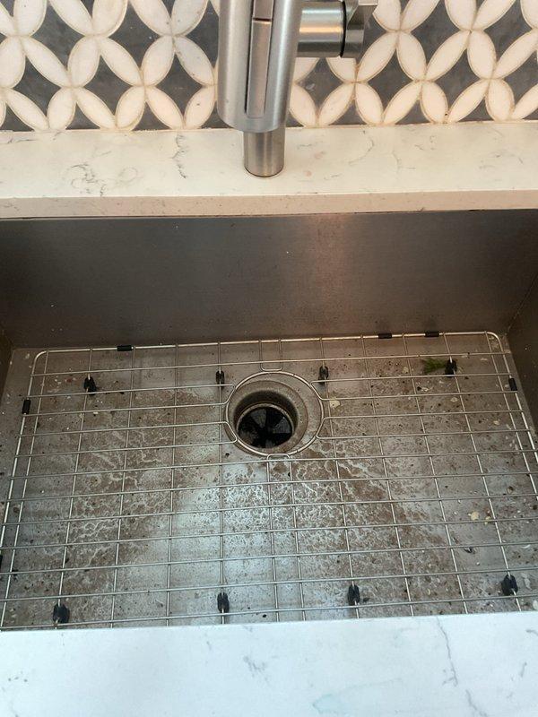 Responded to kitchen sink drainage issue where basin was draining very slowly and only functioning when garbage disposal was activated. Upon inspection, identified obstruction in the drainage system beneath the sink. Cleared blockage from P-trap and drainage pipes, restoring proper water flow through the dark stainless steel sink basin. Verified garbage disposal operation and confirmed all plumbing connections were secure and functioning correctly. System now draining properly without requiring disposal activation.