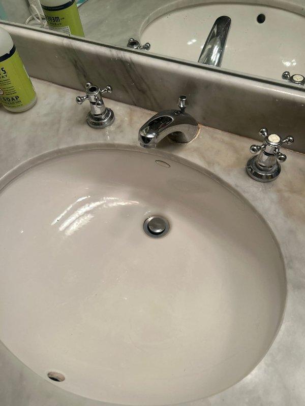 Provided estimate for cartridge replacement on two master bathroom fixtures in second-floor condo unit. Master bath sink features traditional three-hole configuration with separate hot and cold cross-handle valves and curved spout; leak identified at hot water handle stem occurring during operation. Master bath shower equipped with Grohe single-handle pressure-balance valve; experiencing post-closure drip from showerhead. Estimate prepared for replacement of cartridges in both fixtures, with unit shutoff valve confirmed available for isolation during service.