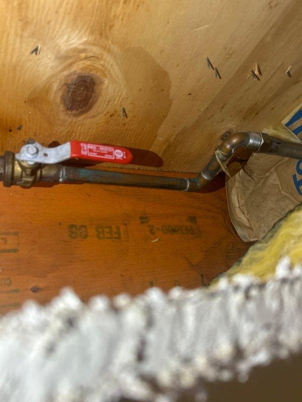Responded to emergency call for water leak affecting basement ceiling when outdoor spigot was activated. Accessed plumbing through ceiling opening to locate source of leak in supply line serving exterior hose bib. Installed new ball valve with red handle and brass elbow fitting on copper supply line within ceiling cavity. Tested system for proper operation and verified no additional leaks present after repairs completed.