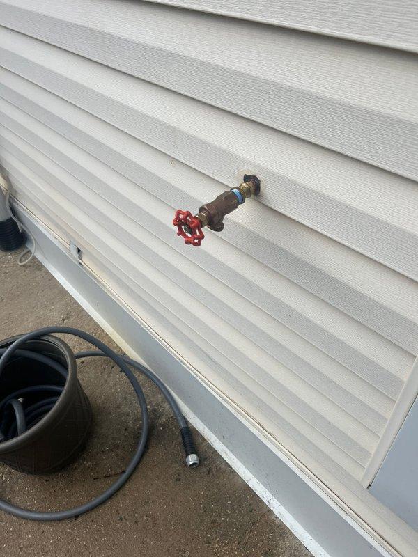 Completed assessment of exterior hose bib with red valve handle and interior gas meter installation with associated piping system. Inspected outdoor water faucet mounted on vinyl siding and evaluated basement gas meter connections including copper, black iron, and yellow CSST gas lines. Documentation captured condition of all visible plumbing and gas infrastructure, pipe supports, and mounting brackets for pre-repair evaluation. Payment to be collected prior to scheduled repair work.