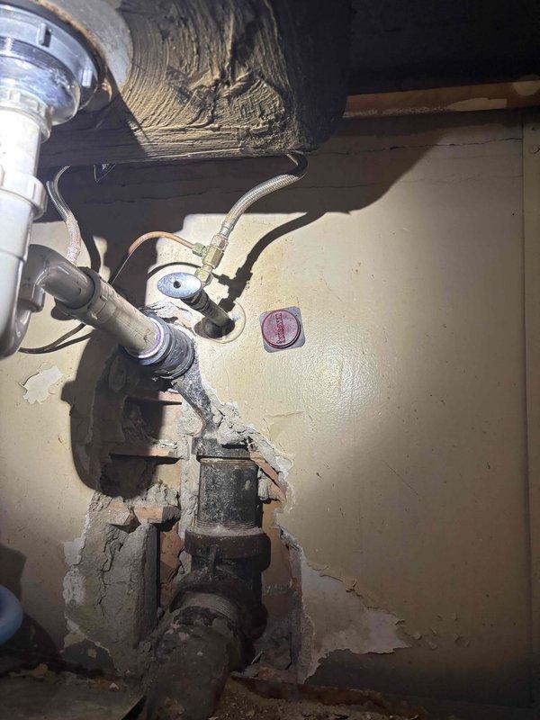 Conducted site assessment in unit 104 to update previous piping estimate. Documented existing conditions of parking garage mechanical infrastructure, including extensive overhead HVAC ductwork, insulated piping systems, and electrical conduit routing. Photographed water heater installation showing deteriorated base conditions, corroded connections, and aging plumbing components requiring replacement or repair in commercial piping estimate revision.