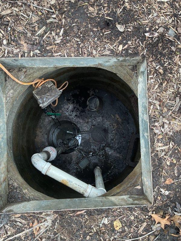 Responded to service call for non-functioning external flood prevention system at 60-year-old residential property. Upon inspection, discovered issues with underground sump pit and drainage well system located in yard near street. Accessed deep concrete cistern well with precast construction showing age-related weathering and moisture accumulation. Inspected suspended pump equipment and monitoring components via access rope system. Examined secondary concrete utility pit containing PVC drainage lines and plumbing connections with standing water present. Assessed pump operation, drainage flow patterns, and structural integrity of both underground containment systems. Documented conditions via photography for maintenance records. System had been inoperative for approximately two days prior to service call, requiring immediate attention to restore flood control functionality and prevent potential property damage.