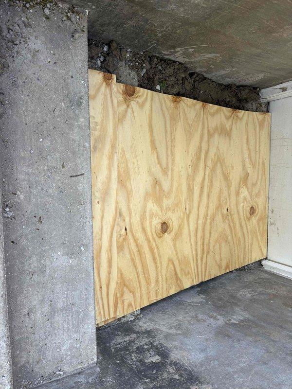 Responded to water intrusion emergency affecting basement access area. Secured compromised entry point with plywood barrier installation to prevent further water damage and unauthorized access. Established safety perimeter with caution tape around affected stairwell due to structural concerns from moisture damage. Documented extensive ceiling deterioration, mold growth, and water staining throughout basement space indicating active leak requiring immediate attention. Temporary weatherproofing measures completed pending full remediation scope development.
