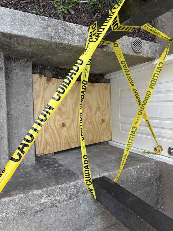 Responded to water intrusion emergency affecting basement access area. Secured compromised entry point with plywood barrier installation to prevent further water damage and unauthorized access. Established safety perimeter with caution tape around affected stairwell due to structural concerns from moisture damage. Documented extensive ceiling deterioration, mold growth, and water staining throughout basement space indicating active leak requiring immediate attention. Temporary weatherproofing measures completed pending full remediation scope development.