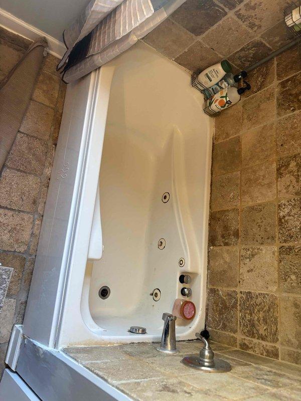 Conducted on-site assessment for replacement of existing 58x30 jetted whirlpool bathtub with standard soaking tub. Evaluated current installation including chrome fixtures, stone tile surround, and plumbing connections to determine scope of work for future tub replacement. Documented existing jetted tub configuration and surrounding tile work to provide accurate estimate for removal and installation of traditional bathtub unit.