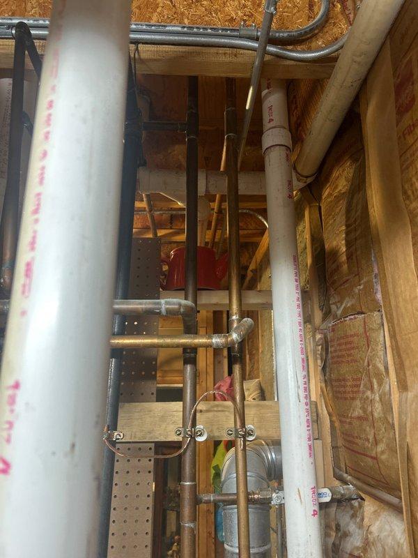 Completed outdoor spigot/shower installation with copper supply line rough-in through exterior wall framing. Installed manifold system with multiple valve connections, secured all piping with proper mounting brackets and strapping to code, and integrated PVC drain line for proper water discharge from outdoor fixture.