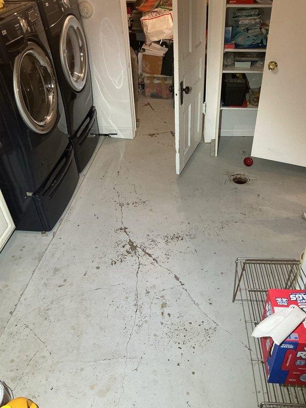 Conducted site assessment for drain tile installation in basement laundry area. Evaluated existing floor conditions, including concrete surface with visible cracking and floor drain location. Documented structural access points and utility routing spaces to determine optimal drain tile placement and estimate scope of work required for proper basement waterproofing system installation.