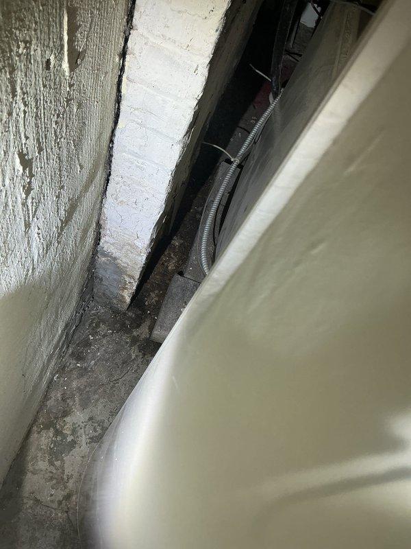 Conducted site assessment for drain tile installation in basement laundry area. Evaluated existing floor conditions, including concrete surface with visible cracking and floor drain location. Documented structural access points and utility routing spaces to determine optimal drain tile placement and estimate scope of work required for proper basement waterproofing system installation.