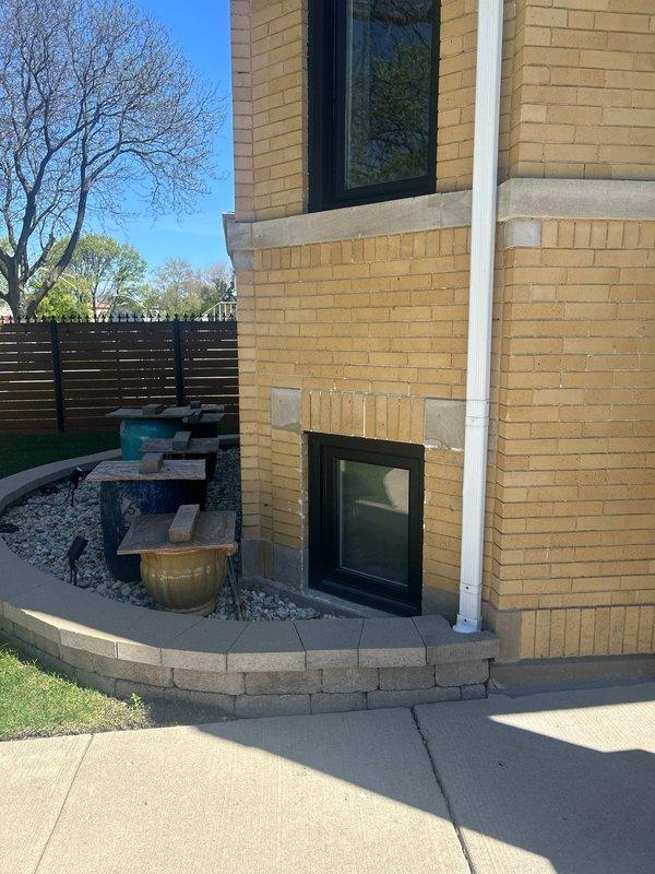 Conducted on-site assessment for flood control system installation at 30-year-old residential property. Evaluated front yard drainage patterns, existing downspout locations, and grading conditions around home's perimeter. Photographed current exterior drainage infrastructure including downspouts, ground-level transitions, and concrete walkway areas to document pre-installation conditions and determine optimal system placement for effective water diversion and property protection.