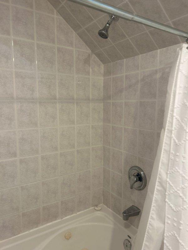 Responded to multiple plumbing concerns including slow draining fixtures and noisy plumbing. Inspected upstairs bathroom shower assembly, bathtub fixtures, and drainage system where customer reported unusual noise during shower operation. Evaluated kitchen faucet experiencing loud operational noise and assessed upstairs bathroom vanity marked for replacement. Documented existing plumbing infrastructure including water heater connections and supply lines in utility area to determine source of drainage issues and fixture noise complaints.