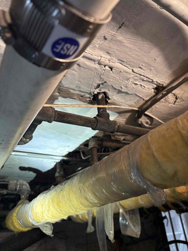Responded to service call for multiple plumbing concerns including hydro jetting estimate, second floor bathroom sink leak penetrating into basement through suspected wall piping, kitchen line repair assessment, and full home plumbing replacement evaluation. Conducted thorough inspection of accessible plumbing infrastructure, documenting deteriorated pipe insulation with compromised vapor barrier wrapping and significant structural damage to surrounding subflooring materials. Assessed exterior foundation penetrations and observed advanced weathering of building envelope components with moisture intrusion indicators. Provided comprehensive estimates for hydro jetting services to clear drainage lines, bathroom sink leak repair with potential wall pipe replacement, kitchen line restoration, and whole-house repiping options to address aging plumbing system throughout the property.