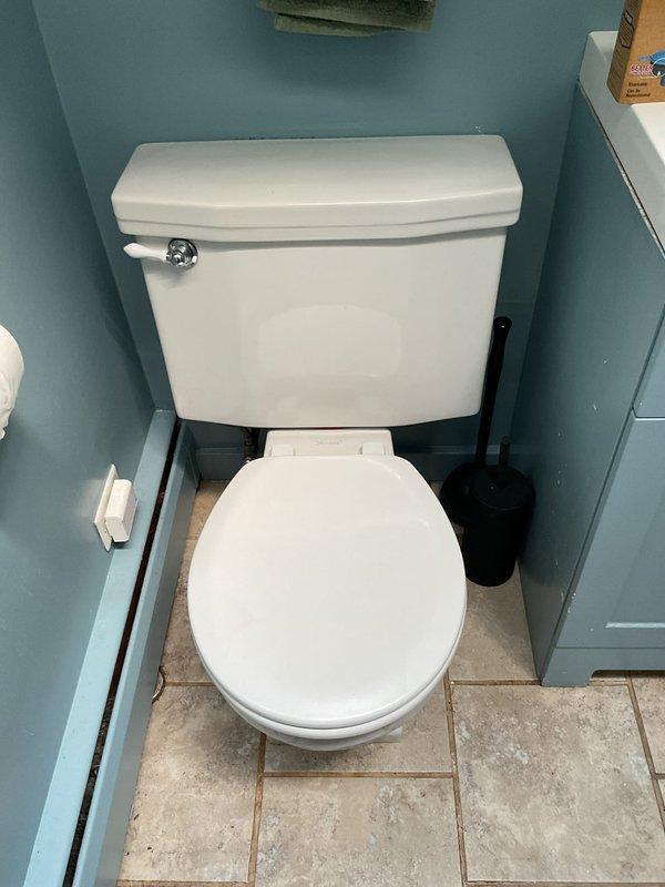 Responded to priority service call for toilet repair in residential bathroom. Customer had attempted DIY wax ring replacement but encountered spinning closet bolts that prevented nut removal. Upon arrival, assessed two-piece white porcelain toilet with corroded closet bolt assembly. Used rotary cutting tool to remove seized closet bolts that could not be loosened conventionally. Removed toilet from floor flange, scraped old wax ring residue from both toilet base and floor flange, and inspected flange for damage. Installed new wax ring with integrated flange sleeve for improved seal. Secured toilet to floor using new brass closet bolts and washers, ensuring proper alignment and level positioning. Tightened mounting nuts to manufacturer specifications to prevent rocking while avoiding over-compression of porcelain base. Reconnected water supply line and tested flush mechanism for proper operation. Verified seal integrity by checking for water leakage at base during multiple flush cycles.