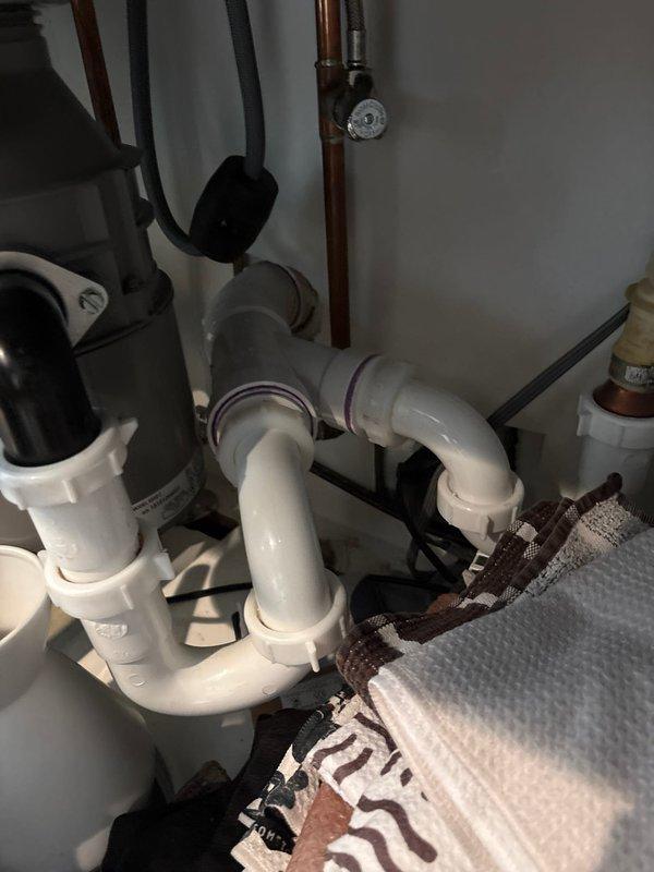 Completed installation of under-sink water filtration system for kitchen fixture. Integrated new filter unit with existing plumbing configuration, which included garbage disposal and PVC drain assembly, ensuring proper water supply connections and secure mounting within cabinet space.