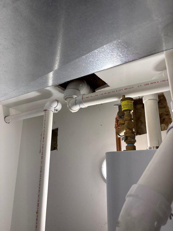 Responded to morning appointment request for plumbing repair assessment. Inspected under-sink plumbing configuration including white PVC drainage system with multiple fittings and connections, brass shut-off valve with pressure relief capabilities, and ceiling-mounted PVC supply lines rated at 280 PSI. Documented existing installation showing standard residential water supply and drainage components, ceiling access point with rough-cut opening for pipe routing, and overall system configuration for repair proposal.