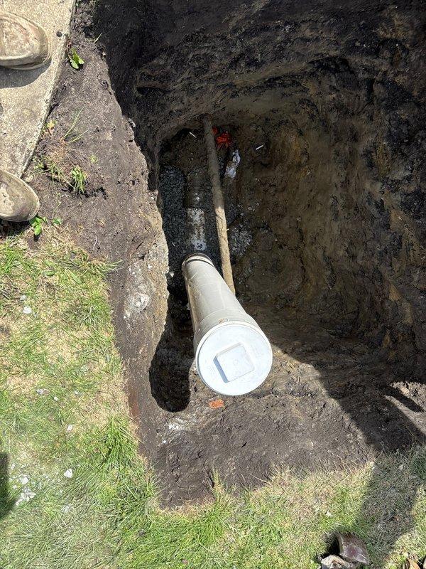 Completed sewer line installation requiring excavation and trenching through residential property. Installed new white PVC sewer pipe with proper coupling connections in prepared trench, ensuring correct slope and alignment for optimal drainage flow. Backfilled excavation upon completion of installation and connection verification.
