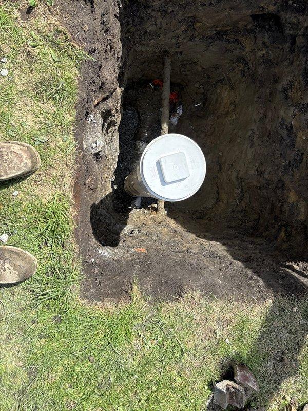 Completed sewer line installation requiring excavation and trenching through residential property. Installed new white PVC sewer pipe with proper coupling connections in prepared trench, ensuring correct slope and alignment for optimal drainage flow. Backfilled excavation upon completion of installation and connection verification.