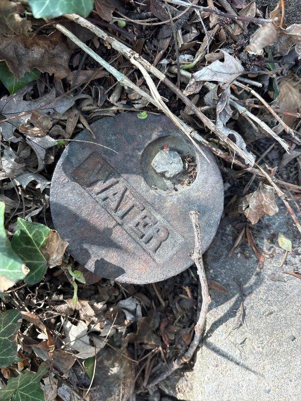 Completed installation of water service cleanout cover at exterior property access point. Replaced corroded and weathered cast iron cleanout cap with new fixture, ensuring proper seal and accessibility for future maintenance needs.