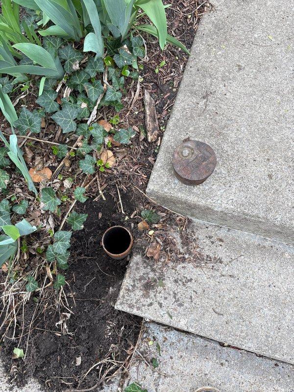 Completed installation of water service cleanout cover at exterior property access point. Replaced corroded and weathered cast iron cleanout cap with new fixture, ensuring proper seal and accessibility for future maintenance needs.