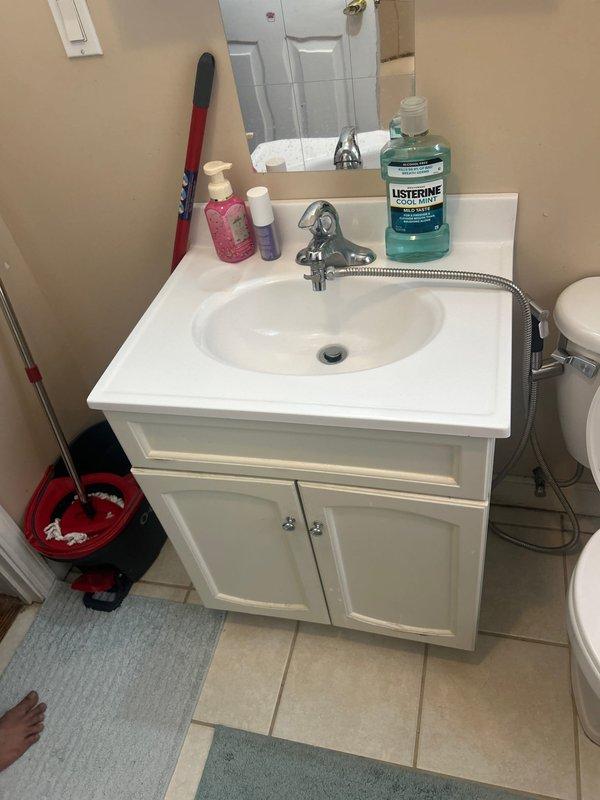 Conducted comprehensive plumbing inspection of residential bathroom vanity and sink assembly. Documented existing fixture conditions including chrome single-handle faucet with pull-out sprayer, white integrated vanity basin, and associated supply line connections. Inspected undersink plumbing components including braided stainless steel flexible supply lines, copper piping, faucet mounting hardware, and drain assembly for potential issues or required maintenance.
