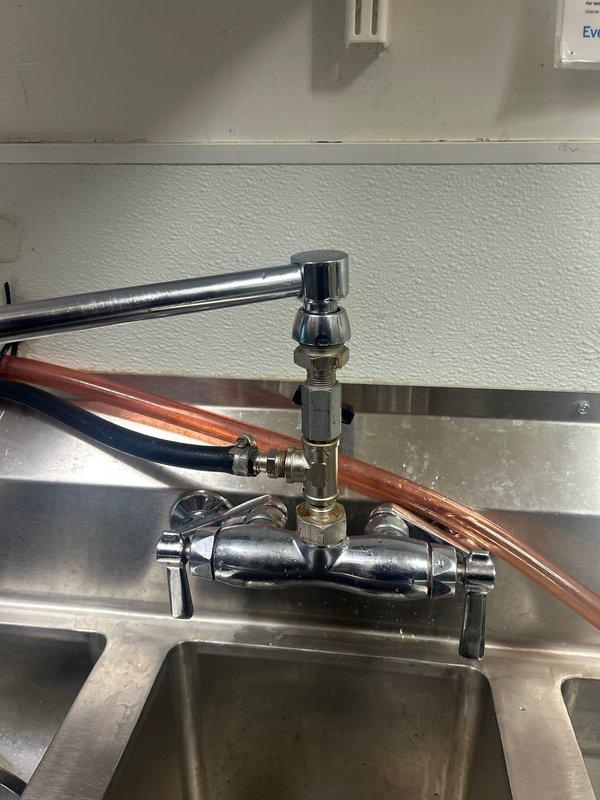 Responded to a commercial kitchen plumbing emergency where the sink faucet assembly had completely broken off from the mounting point. Replaced the failed chrome pull-out spray faucet unit, reconnected copper supply lines with new brass compression fittings, and installed replacement flexible hoses to restore full water service to the stainless steel sink basin.