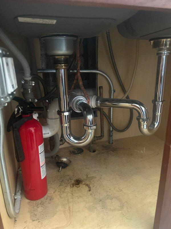 Completed installation of chrome single-handle kitchen faucet on double-basin stainless steel sink with light gray speckled countertop. Verified proper connection to existing plumbing infrastructure including P-trap assembly and garbage disposal unit, confirmed no leaks at all connection points, and tested full water flow and temperature control functionality.