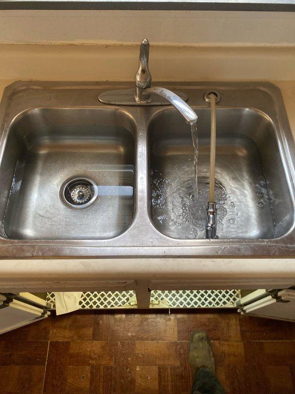 Responded to a plumbing service call for kitchen sink evaluation and repair. Inspected double-basin stainless steel sink installation with chrome faucet assembly and spray attachment. Assessed water flow and drainage system functionality in both basins. Created access opening through ceiling to expose overhead plumbing infrastructure, including copper water supply lines, PVC drain and vent piping, and associated utility conduits running through floor joists. Evaluated condition of soldered copper joints and plastic drainage connections within the structural cavity. Documented existing plumbing configuration and system layout for repair recommendations. Job sold for necessary plumbing repairs identified during inspection.
