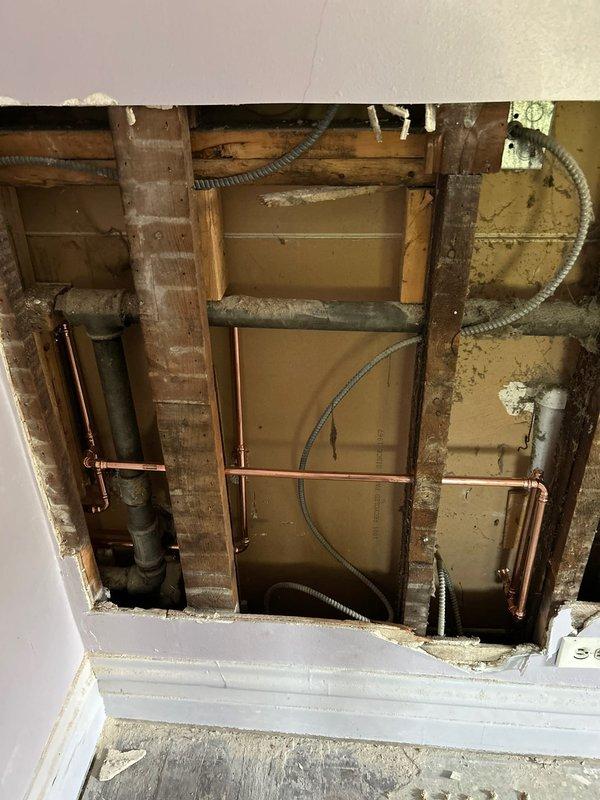 Responded to a plumbing service call for kitchen sink evaluation and repair. Inspected double-basin stainless steel sink installation with chrome faucet assembly and spray attachment. Assessed water flow and drainage system functionality in both basins. Created access opening through ceiling to expose overhead plumbing infrastructure, including copper water supply lines, PVC drain and vent piping, and associated utility conduits running through floor joists. Evaluated condition of soldered copper joints and plastic drainage connections within the structural cavity. Documented existing plumbing configuration and system layout for repair recommendations. Job sold for necessary plumbing repairs identified during inspection.