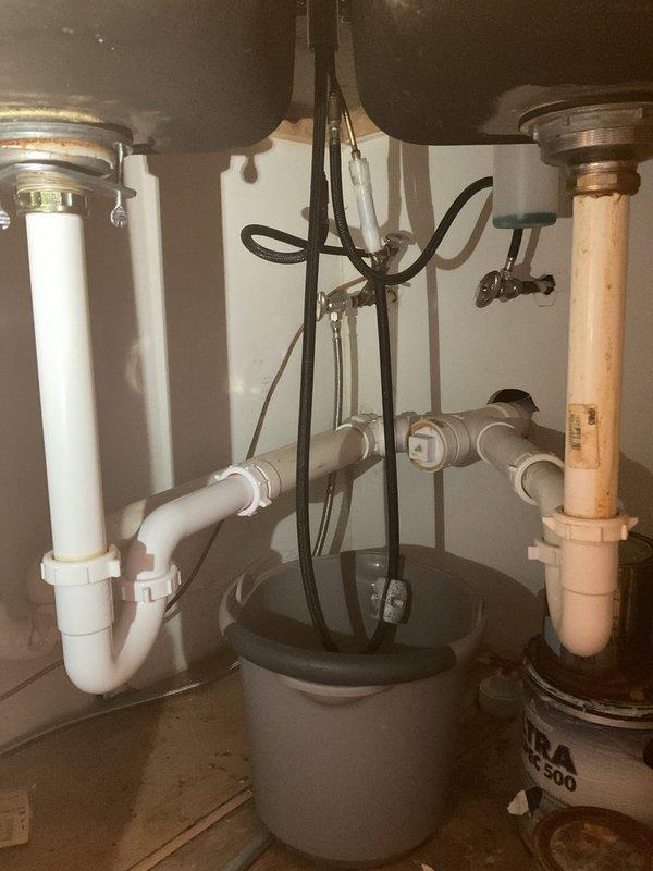 Responded to water leak complaint originating from kitchen sink and affecting the unit below. Conducted visual inspection of kitchen sink area and under-sink plumbing configuration, documenting conditions with photos. Advised that access to both the upper unit (source) and lower unit (affected area) would be required to complete thorough leak investigation and determine exact source of water intrusion. Awaiting confirmation of access to lower unit before proceeding with comprehensive leak location service and necessary repairs.