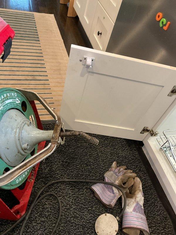 Responded to kitchen sink backup with complete drainage failure. Upon arrival, confirmed no visible blockages in disposal or p-trap as previously checked. Deployed professional drain cleaning equipment with power auger to access main drain line beneath sink cabinet. Successfully cleared significant blockage in drain line that had been causing progressive slow drainage over previous 1-2 months before complete stoppage occurred. Ran water to verify full drainage restoration and proper flow rate. System tested and functioning normally upon completion.