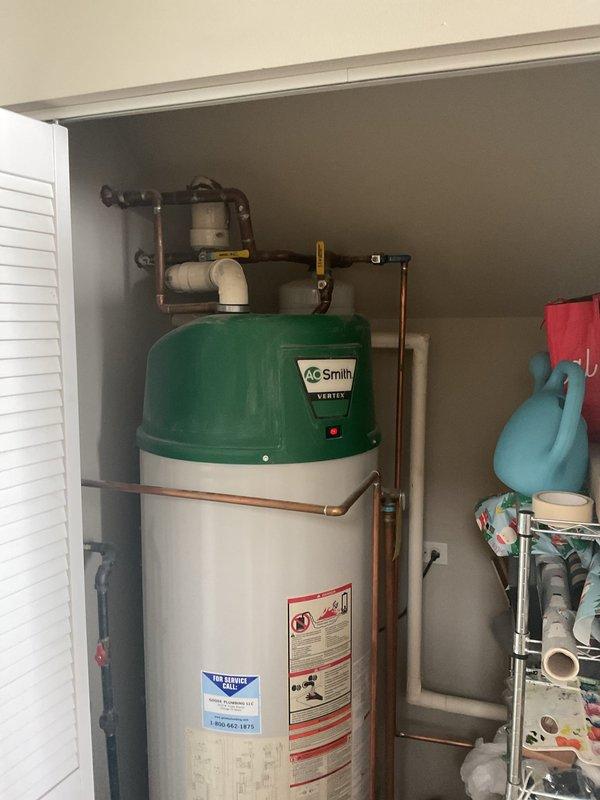 Responded to service call for leaking water heater. Upon inspection, identified an AO Smith VERTEX water heater with active leak from piping connection. Evaluated unit condition, plumbing connections, and surrounding installation components including copper supply lines, drip pan, and associated water treatment system to provide comprehensive estimate for repair or replacement options.