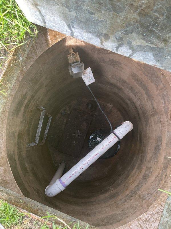 Performed comprehensive inspection of EverReady flood control system at residential property constructed in 1950. Accessed exterior sump pit and verified operational status of submersible pump and associated electrical components. Inspected pit interior for structural integrity, noting age-appropriate staining on concrete walls and proper water level at basin bottom. Confirmed PVC discharge piping configuration and verified float switch cable positioning. System components showed normal wear consistent with home age but maintained functional operation. Photographically documented pit condition and equipment placement for service records.