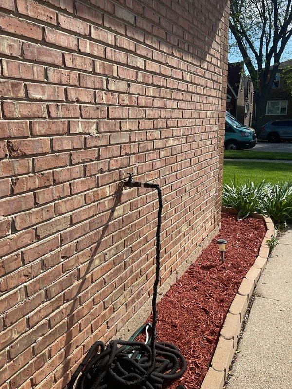 Responded to customer request for plumbing inspection regarding pipe replacement at residential property. Conducted thorough visual assessment of exterior water supply system, including hose bib mounted on brick foundation wall and underground utility access point. Documented existing piping conditions through photographic evidence, noting black pipe routing through below-grade access pit with visible cable tie securing methods. Inspection revealed aging infrastructure with weathered concrete surfaces and potential access points for future pipe replacement work.