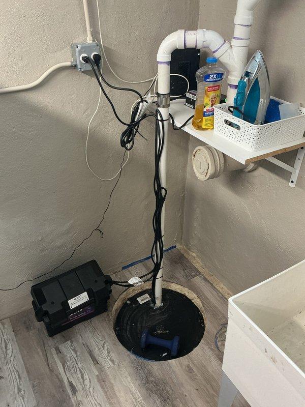 Responded to callback request to evaluate existing sump pump system for potential addition of bypass discharge line. Conducted on-site assessment of current installation, which includes blue submersible pump in floor basin with electrical control box and standard discharge piping configuration. Documented existing system setup with photographs showing pump location in utility area, current PVC discharge routing, and electrical connections. Discussed bypass discharge line options with customer to provide redundant drainage capability and prevent potential overflow situations. Provided technical recommendations for installation approach and system modifications required.