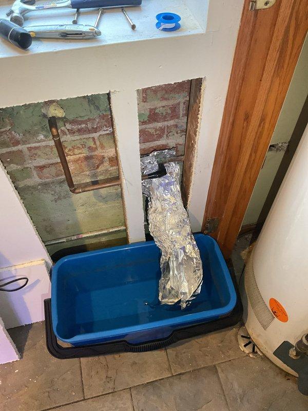 Responded to emergency call for active leak from burst pipe supplying outdoor water spigot. Accessed affected piping through interior wall by creating access openings in drywall, exposing brick masonry and compromised copper supply line. Isolated and replaced damaged section of copper piping with new copper pipe and fittings. Installed temporary collection system to manage water during repair. Insulated exposed piping to prevent future freeze damage. Tested system for proper flow and verified no additional leaks present. Wall access points left open for customer inspection and future closure.