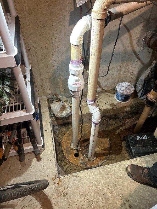 Completed waste pump installation in basement utility area with new PVC discharge piping system. Installed vertical discharge lines with proper check valve integration, secured all pipe penetrations through concrete floor with appropriate sealing, and verified system operation. All components installed to code specifications with purple primer applied at joints for proper solvent welding of PVC connections.