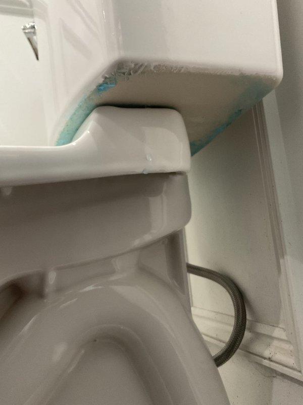 Completed toilet installation in residential bathroom featuring white two-piece porcelain fixture with chrome flush handle. Replaced existing unit that exhibited severe condensation and frost buildup behind tank area, indicating previous supply line or seal failure. New installation includes proper water supply connection, wax ring seal, and secure mounting to ensure leak-free operation and prevent moisture intrusion that caused the crystalline ice formation observed on the previous fixture.