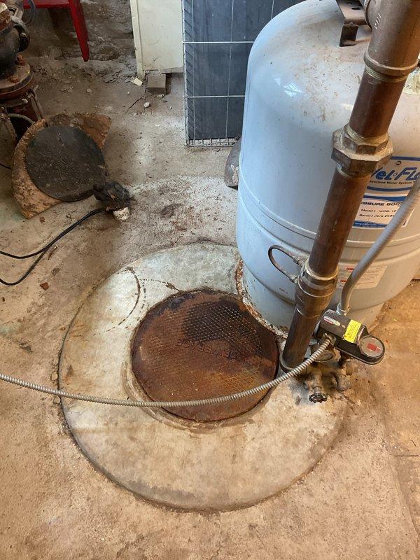 Responded to a flood control system failure caused by a broken check valve in the underground flood control pit. Upon inspection, found the check valve mechanism installed in 2020 had failed, compromising the system's ability to prevent backflow. The galvanized piping showed corrosion and the float mechanism at the base of the concrete pit required replacement. Documented extensive rust staining and deterioration throughout the concrete structure and surrounding floor area, indicating prolonged moisture exposure. Photographed the damaged check valve assembly, corroded piping connections, and the condition of the utility room floor with significant water damage patterns around the drain cover and equipment. Provided assessment and repair recommendations to restore proper flood control system functionality.