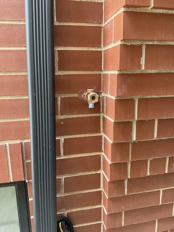 Responded to service call for multiple plumbing leaks including an exterior hose bib, bathroom faucet, and PVC pipe near furnace. Inspected weathered brass outdoor spigot mounted on brick exterior wall showing signs of deterioration and active leak. Evaluated bathroom sink with three-piece chrome faucet assembly featuring separate hot and cold handles and center spout, identifying source of leak at fixture. Documented conditions of both locations with photographs for repair assessment and provided recommendations for necessary repairs to resolve all reported leaking fixtures.