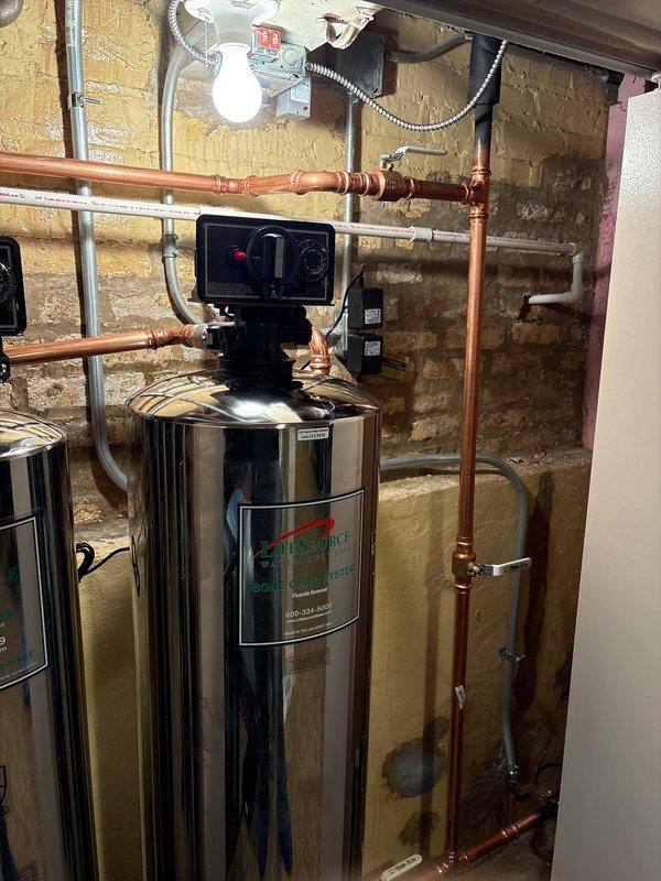 Completed installation of whole-house water filtration system in basement utility area. Installed stainless steel treatment tank with digital control head, integrated system with existing copper supply lines using new piping and compression fittings, and mounted all components to structural framing with proper support brackets. System tested and confirmed operational with all connections secure and leak-free.