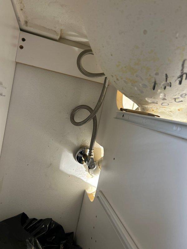 Responded to service call for leaking bathroom faucet with request for replacement. Upon inspection, identified active leak at faucet assembly and additional leak at supply line elbow connection beneath toilet. Observed water damage staining on wall surrounding water supply valve and moisture damage to vanity cabinet interior with discoloration on cabinet surfaces. Documented existing conditions including deteriorated cabinet materials and evidence of prolonged water exposure. Replaced defective bathroom faucet assembly and addressed leaking elbow connection at water supply line to eliminate active water infiltration and prevent further damage to surrounding fixtures and cabinetry.