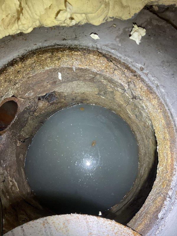 Responded to callback for underground sump pit or utility chamber inspection. Upon arrival, documented existing conditions showing significant sediment buildup, standing water accumulation, and deteriorated interior surfaces with heavy mineral deposits and staining throughout the cylindrical concrete chamber. Identified drainage pipe entry point with visible moisture infiltration patterns and confirmed water level at bottom of pit, indicating potential drainage or pumping system concerns requiring attention.