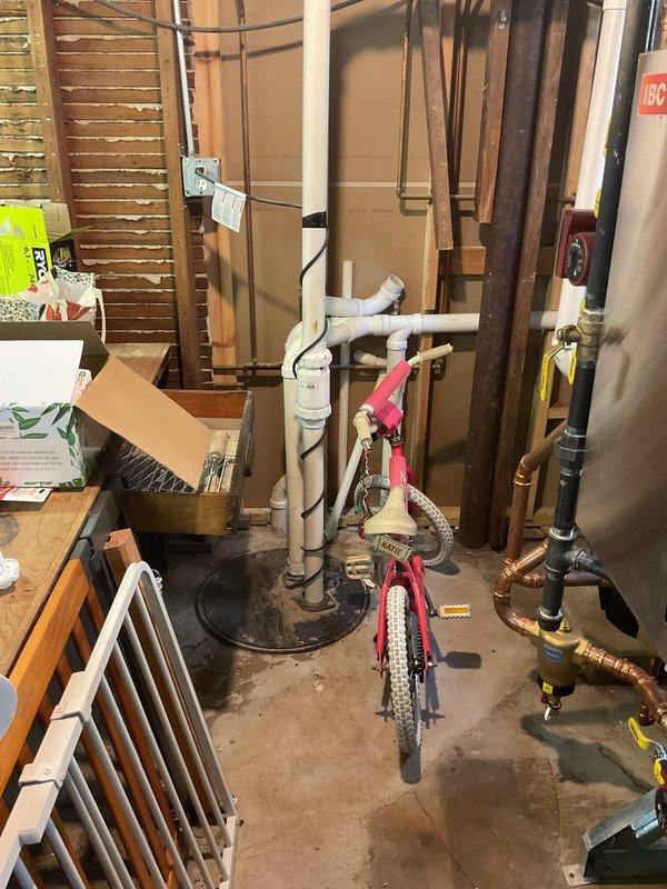 Responded to clogged drain service call and conducted comprehensive inspection of basement plumbing system. Upon arrival, assessed the drainage infrastructure including exposed copper supply lines, PVC drain piping, and floor drain assembly. Documented existing plumbing configuration with copper pipe runs, brass fittings, and drainage connections throughout the mechanical space. Inspected floor drain location and surrounding plumbing components to identify potential blockage points in the drainage system. Photographed the plumbing layout for service records, capturing vertical and horizontal pipe runs, shut-off valves, and connection points along the cinderblock foundation wall.