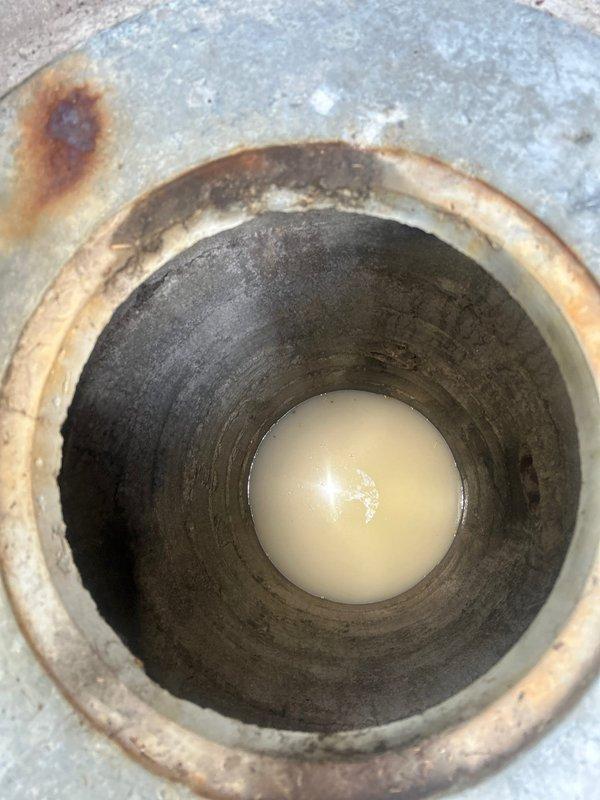 Responded to residential basement flooding concern with water surfacing through floor in area without visible floor drain. Conducted thorough inspection of basement bathroom and surrounding areas to identify source of water intrusion. Documented existing conditions including bathroom fixtures, flooring transitions, and potential drainage access points. Investigated deteriorated cylindrical pipe opening embedded in basement floor showing significant corrosion, rust staining, and standing water with sediment accumulation. Pipe exhibited heavy interior buildup and discoloration consistent with long-term moisture exposure and potential drainage system failure. Photographed evidence of compromised drainage infrastructure and provided estimate for necessary sewer and drain repairs to address water intrusion issue and restore proper drainage function.