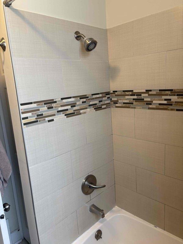 Conducted callback inspection of bathroom shower and tub area to assess condition and document requirements for upcoming estimate. Photographed existing shower valve assembly, tub spout, single-lever handle, and overall bathtub condition, noting visible staining and discoloration on tub surface requiring replacement evaluation.